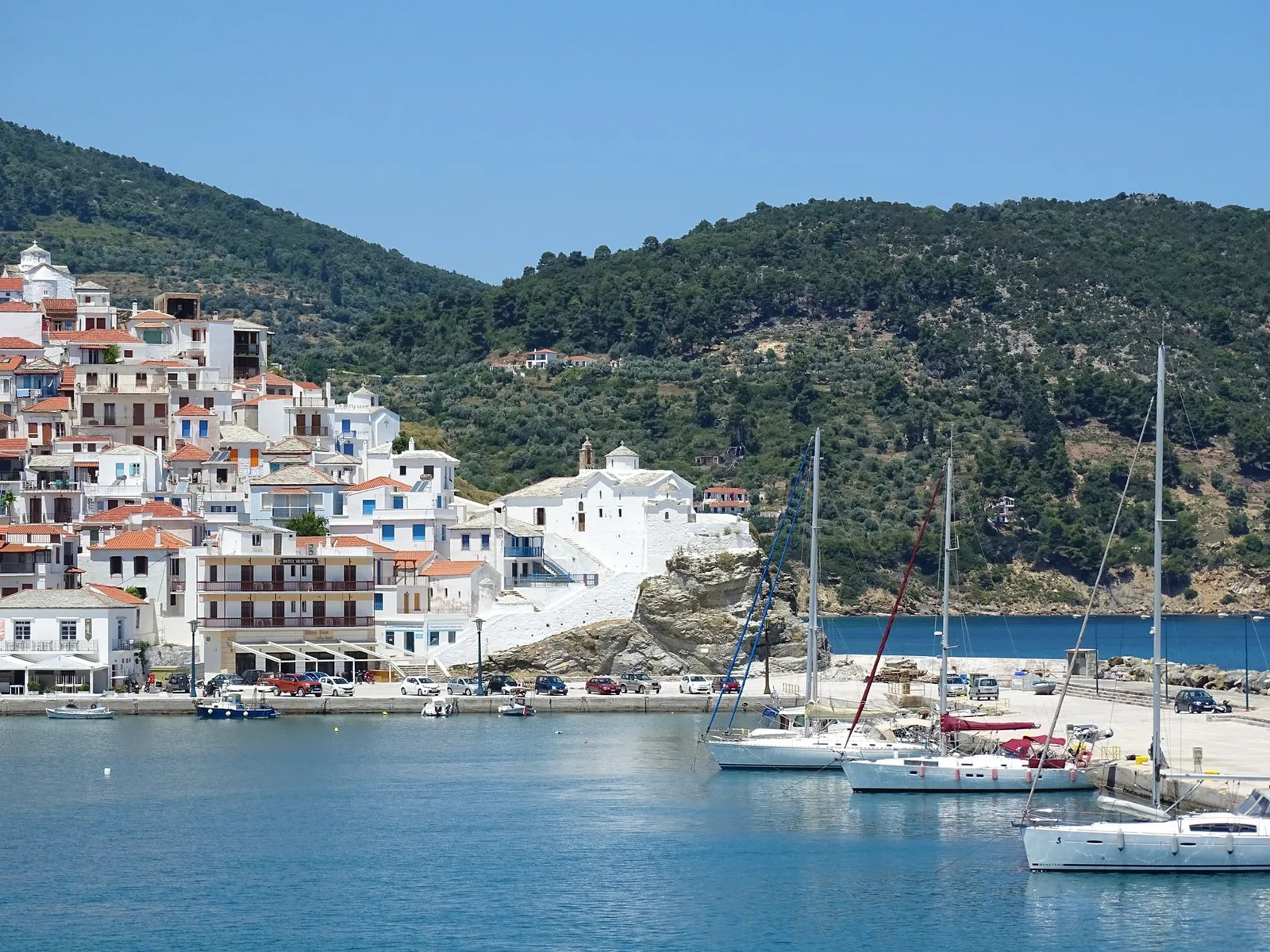 Voiliers amarrés dans le port de Skopelos Ville devant les maisons blanches étagées sur la colline boisée