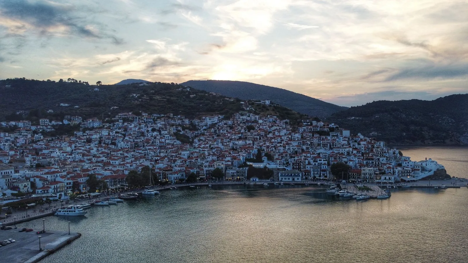 Skopelos Ville et sa baie vues du ciel au crépuscule, les lumières du port reflétées dans l'eau calme