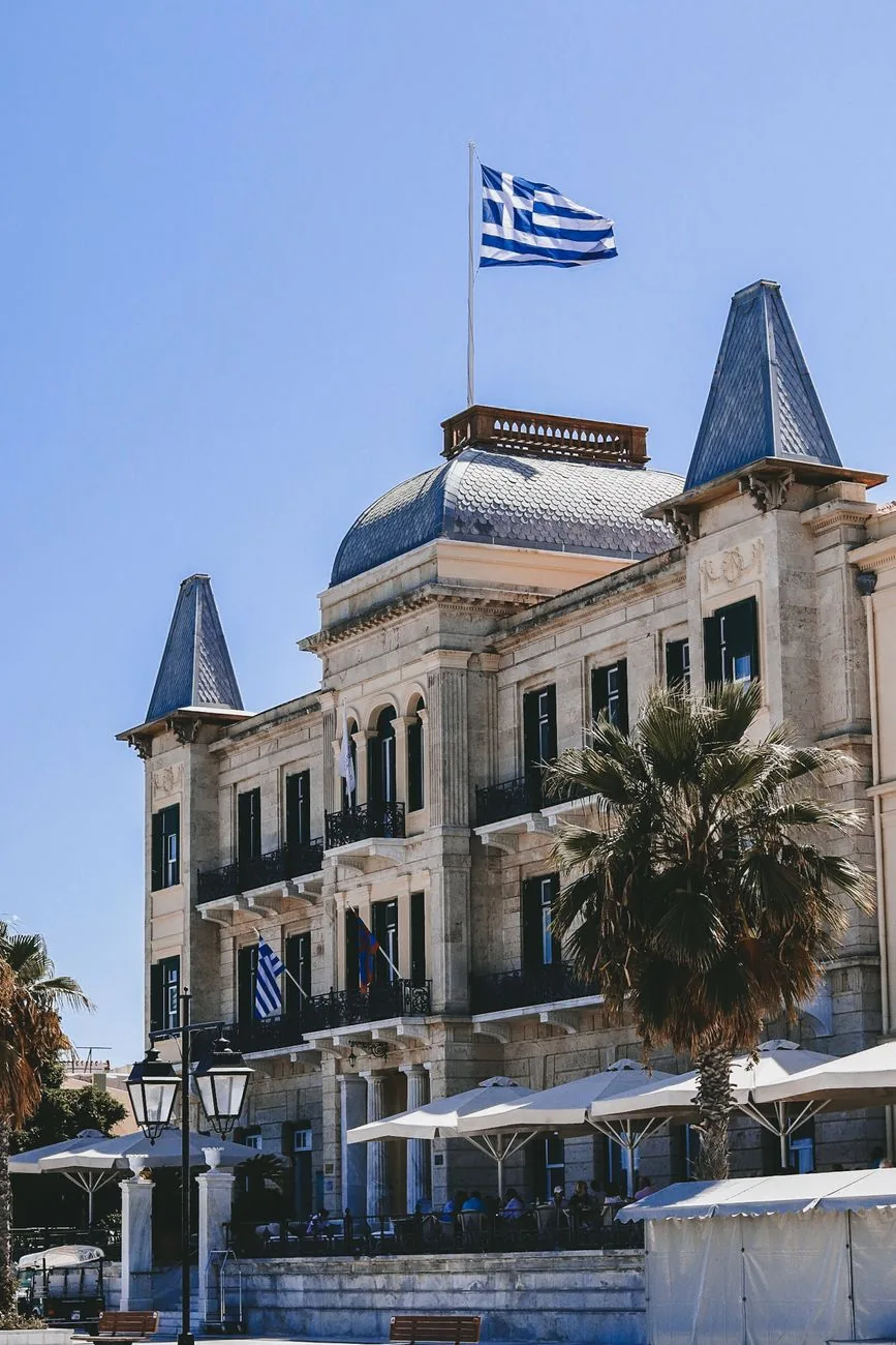 La façade du Poseidonion Grand Hotel, ses deux tourelles et le drapeau grec, sur le front de mer de Dapia à Spetses