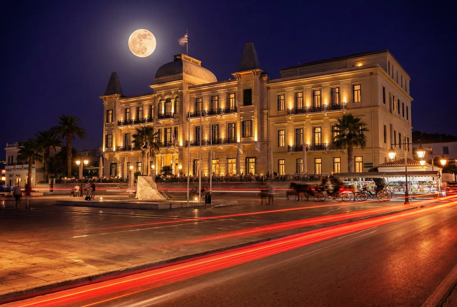 Le Poseidonion Grand Hotel illuminé sous la pleine lune à Spetses, avec les calèches qui attendent sur le front de mer