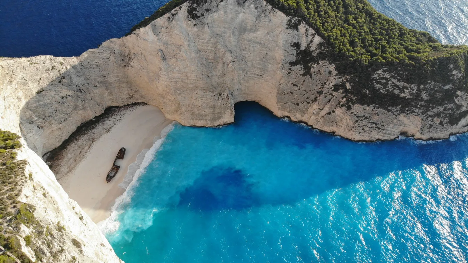 La plage du Navagio et son épave enserrées par des falaises blanches, vue aérienne, à Zante